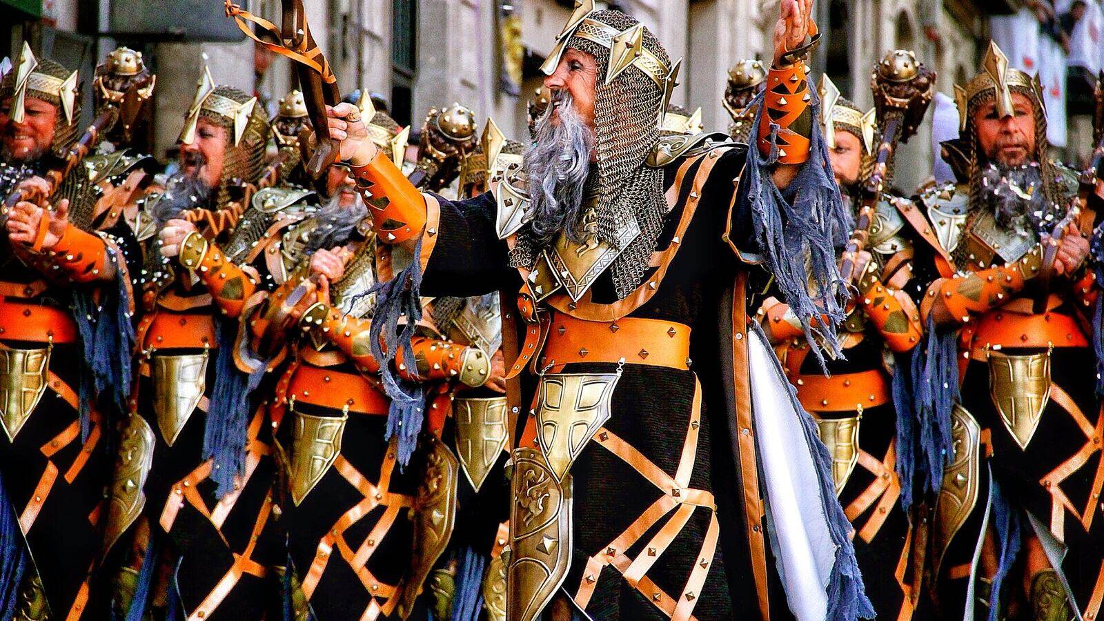 Deelnemers in kleurrijke kostuums tijdens een optocht van Moros y Cristianos