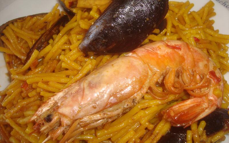 Een pan fideuà met dunne noedels, garnalen en aioli