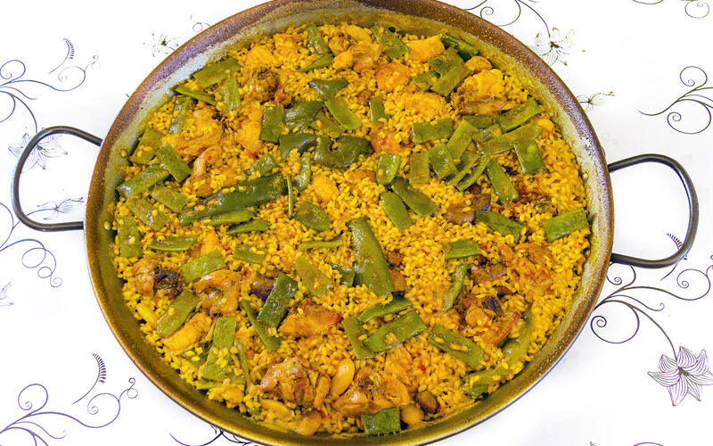 Een pan echte paella valenciana met rijst, kip, konijn en groene bonen