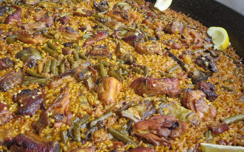 Een grote pan paella valenciana met rijst, kip en groenten